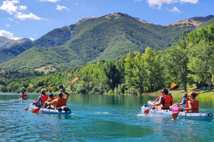 Tre canoe biposto che stanno pagaiando nel lago di Fiastra