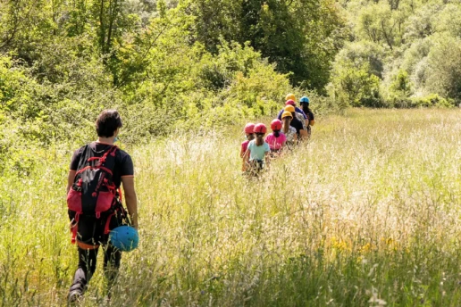 ragazzi con il casco che attraversano un campo e seguiti da un istruttore