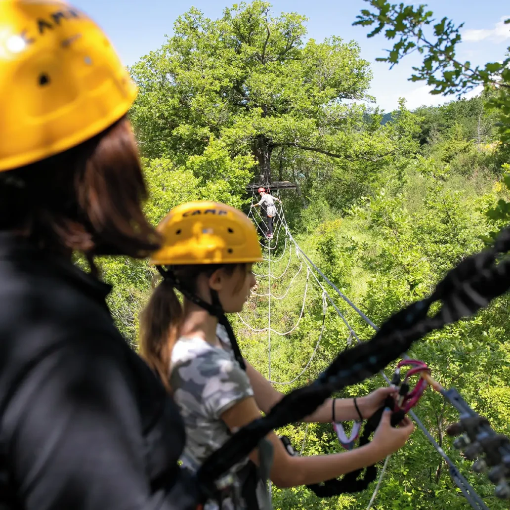 ponte tibetano con tre persone, due in attesa di una terza che lo sta percorrendo