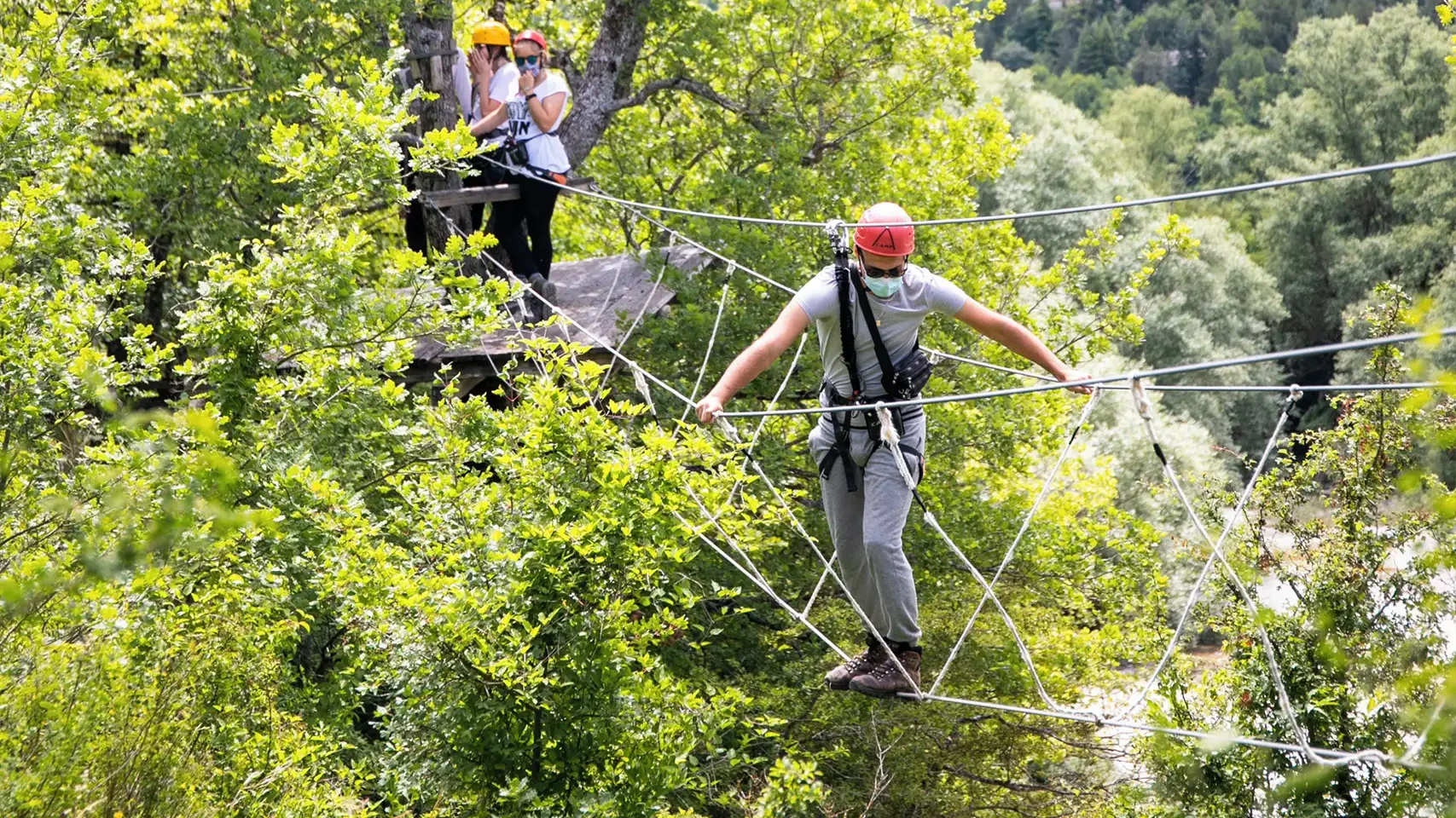 ragazzo che attraversa un ponte tibetano nel parco avventura