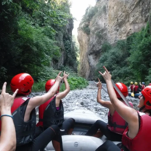 ragazza di spalle, su un gommone rafting in entrata nelle gole del fiume Corno, che fanno le corna con le braccia alzate