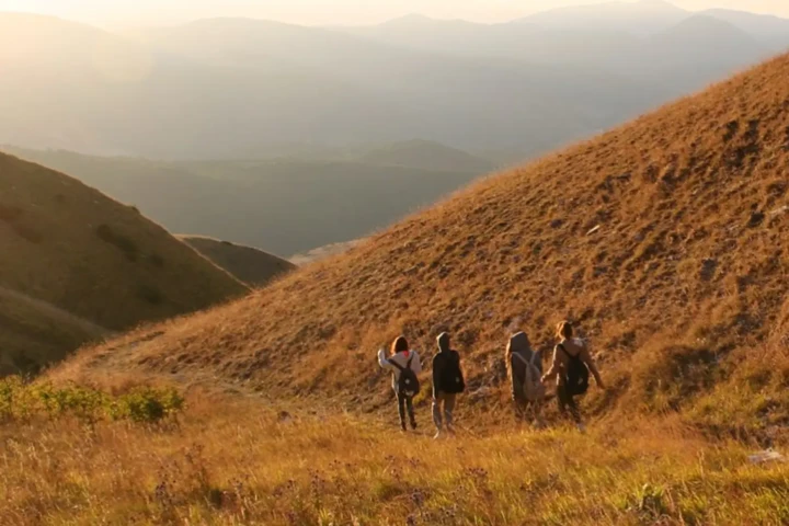 4 ragazza che stanno scendendo dal monte durante un tramonto