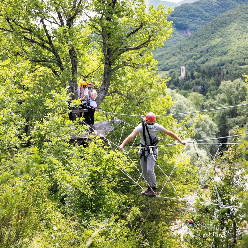ragazzo che attraversa un ponte tibetano nel parco avventura