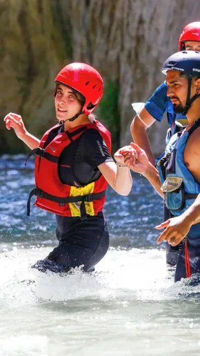 istruttore di rafting che da la mano ad una bella ragazza nel fiume Corno