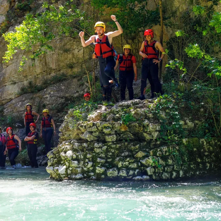 ragazzo con giubbotto che si tuffa nel fiume durante una sosta di rafting
