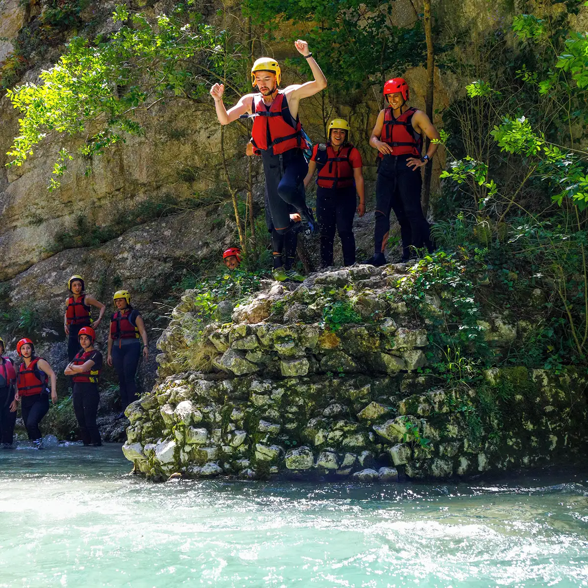 ragazzo con giubbotto che si tuffa nel fiume durante una sosta di rafting